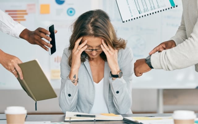 Femme stressée à son bureau, la tête entre les mains