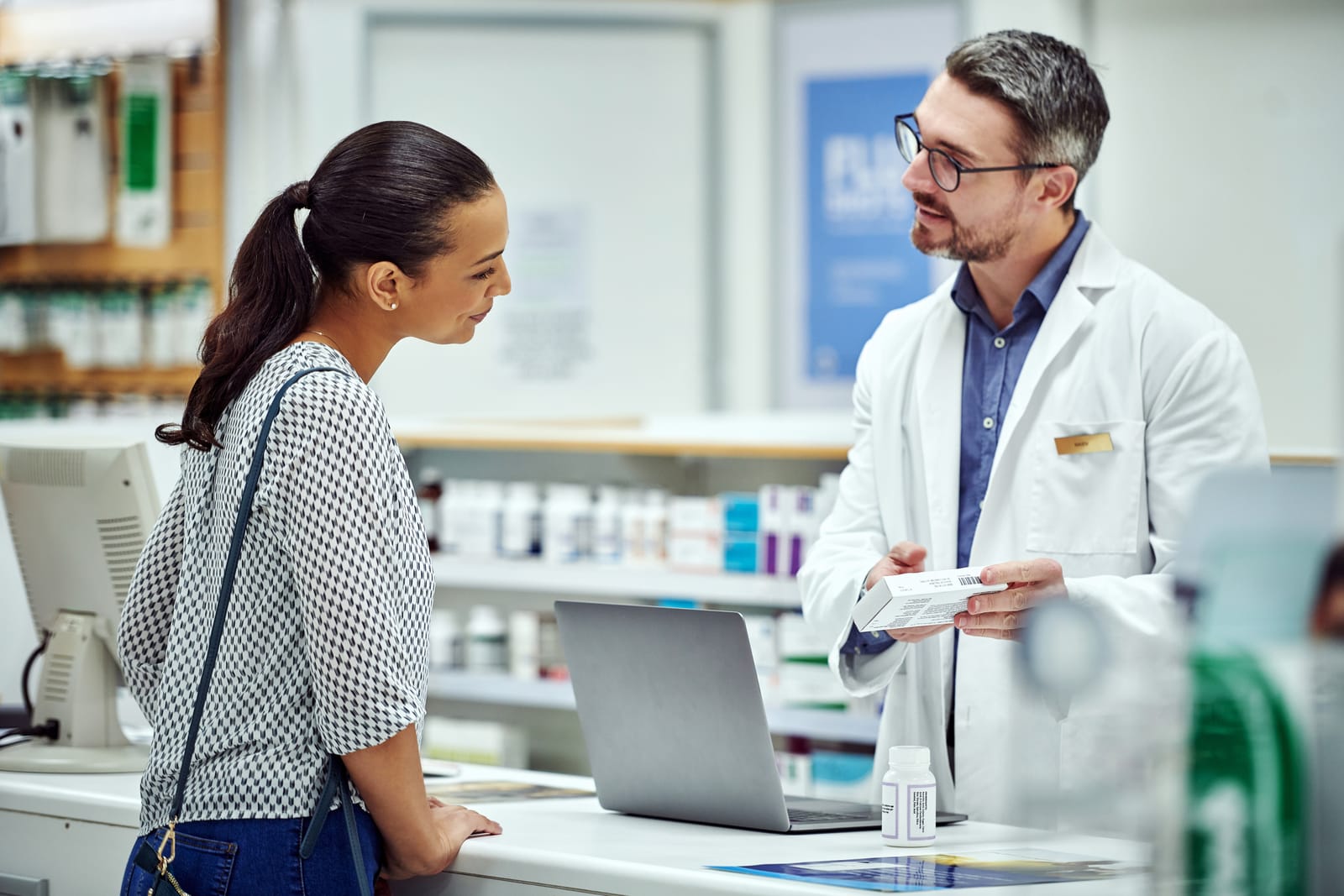 Pharmacien conseillant une cliente au comptoir d'une pharmacie