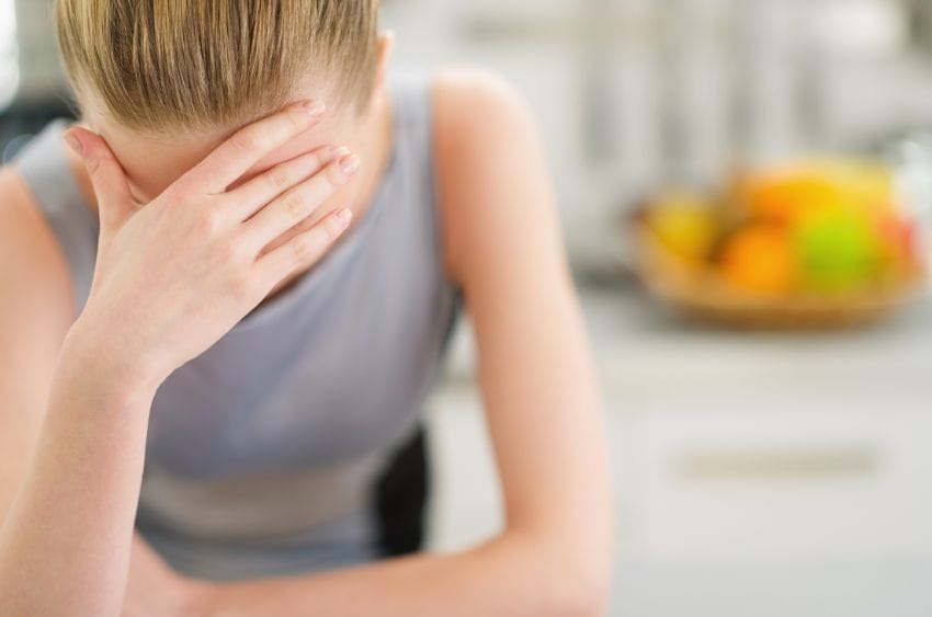 Femme se tenant le front d'une main dans une cuisine