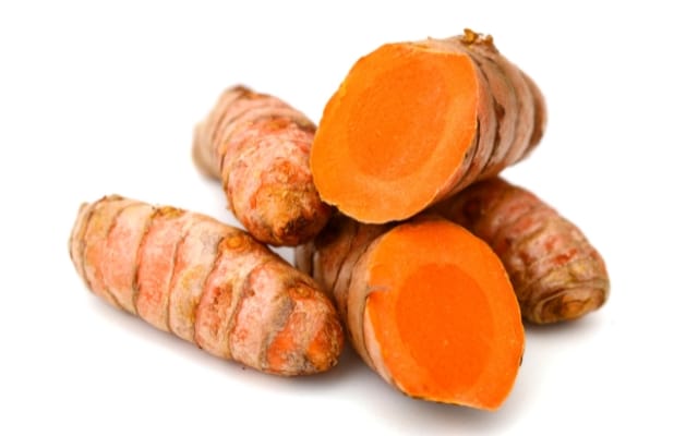 Racines de curcuma fraîches, dont deux coupées en deux