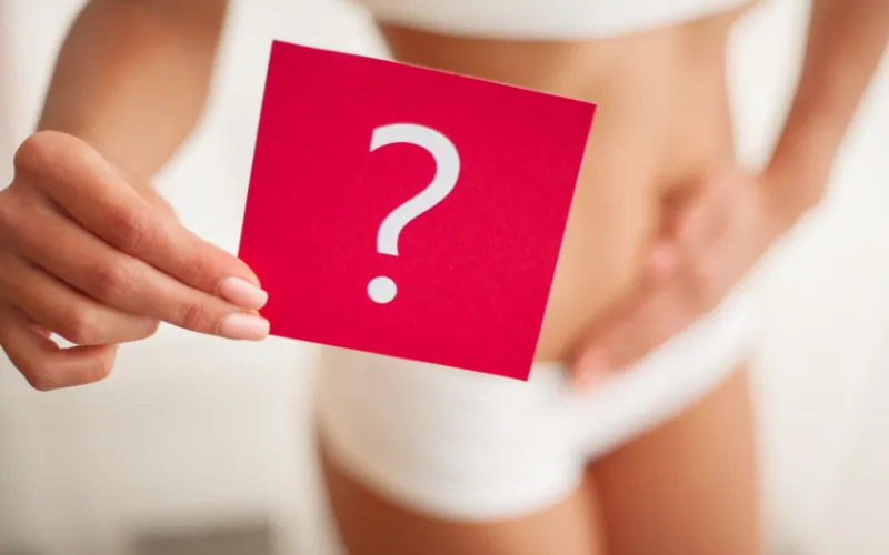 Femme tenant une carte rouge avec un point d'interrogation devant son ventre