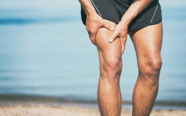 Homme se tenant la cuisse sur une plage