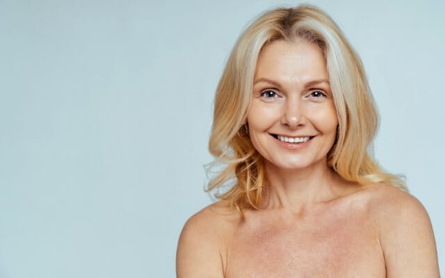 Femme souriante à la peau lisse sur fond clair
